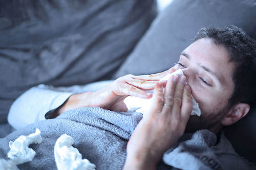 A young man blowing his nose.