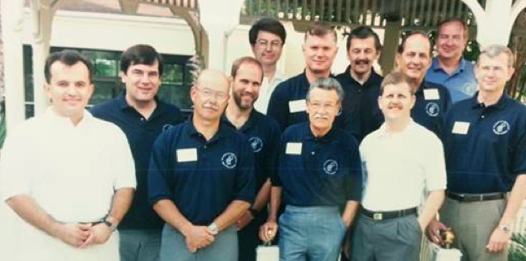 Group photo of early Field Elders, most in matching navy polo shirts with name tags